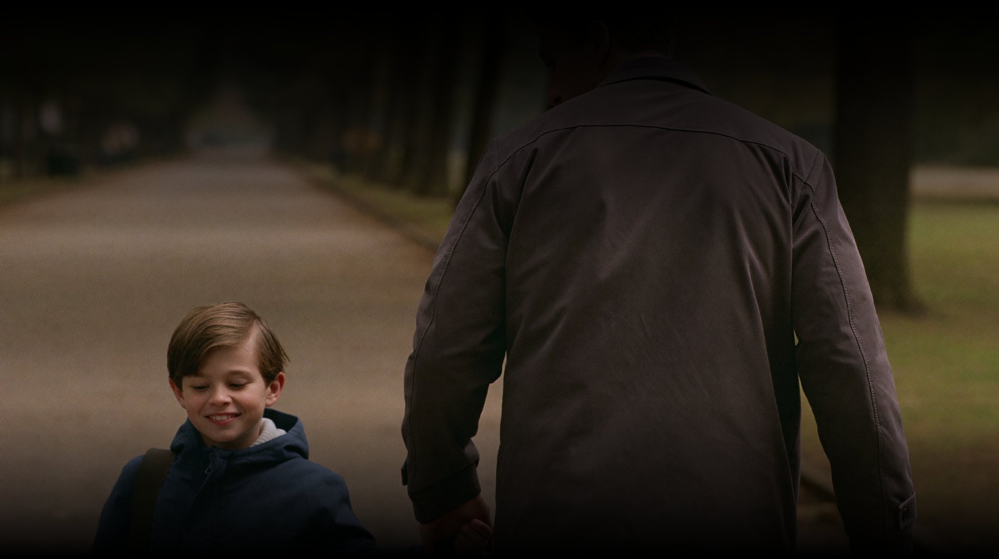 A father and his young son walking together along a path.